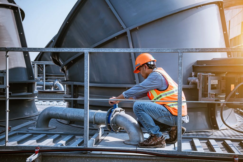 Técnico de refrigeração comercial trabalhando na torre de resfriamento