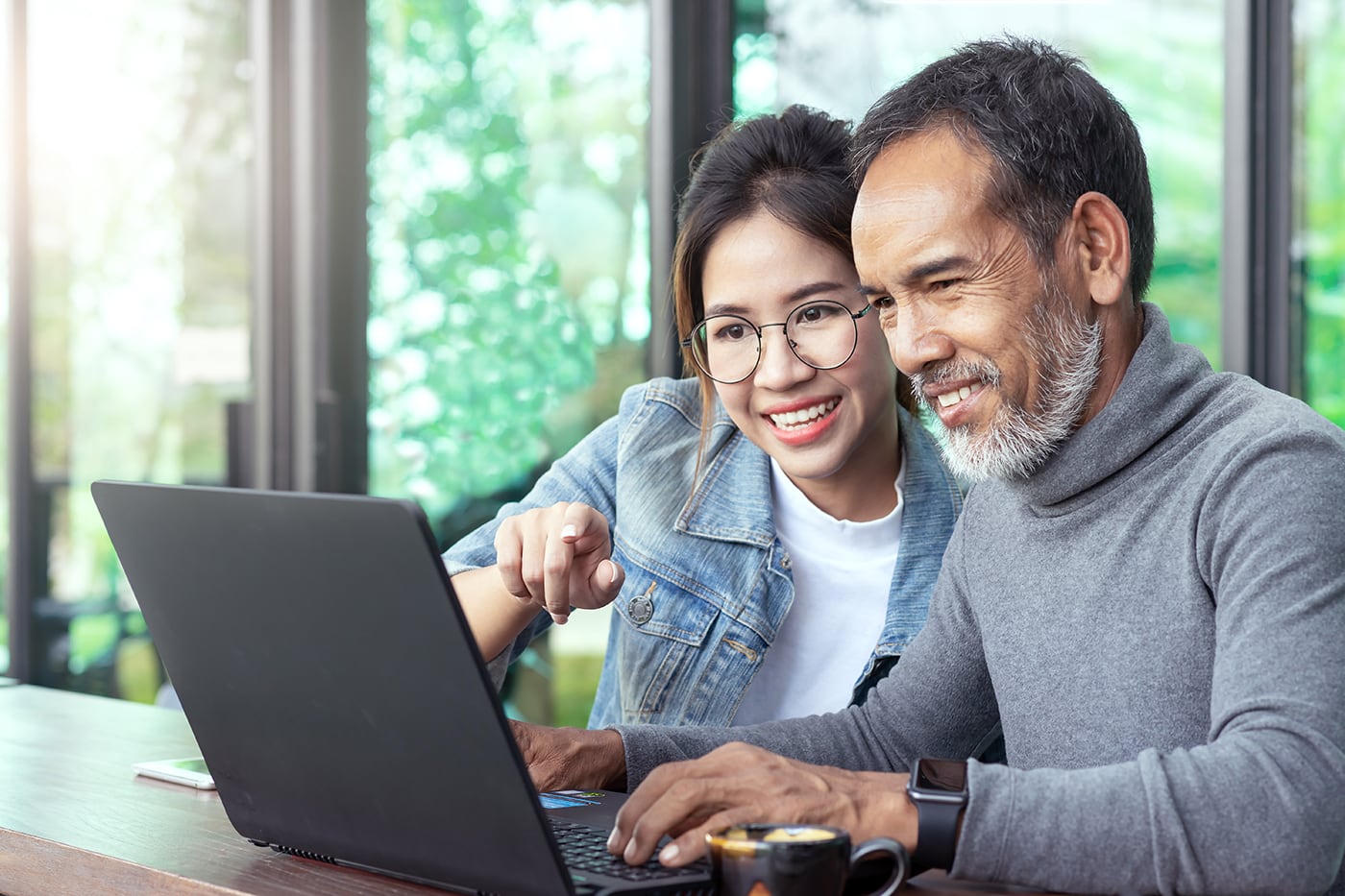 Pai e filha lendo sobre o programa ESL no laptop